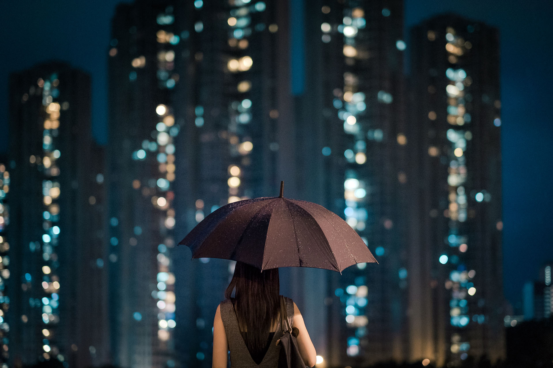 View of a woman from behind looking at a city skyline at night